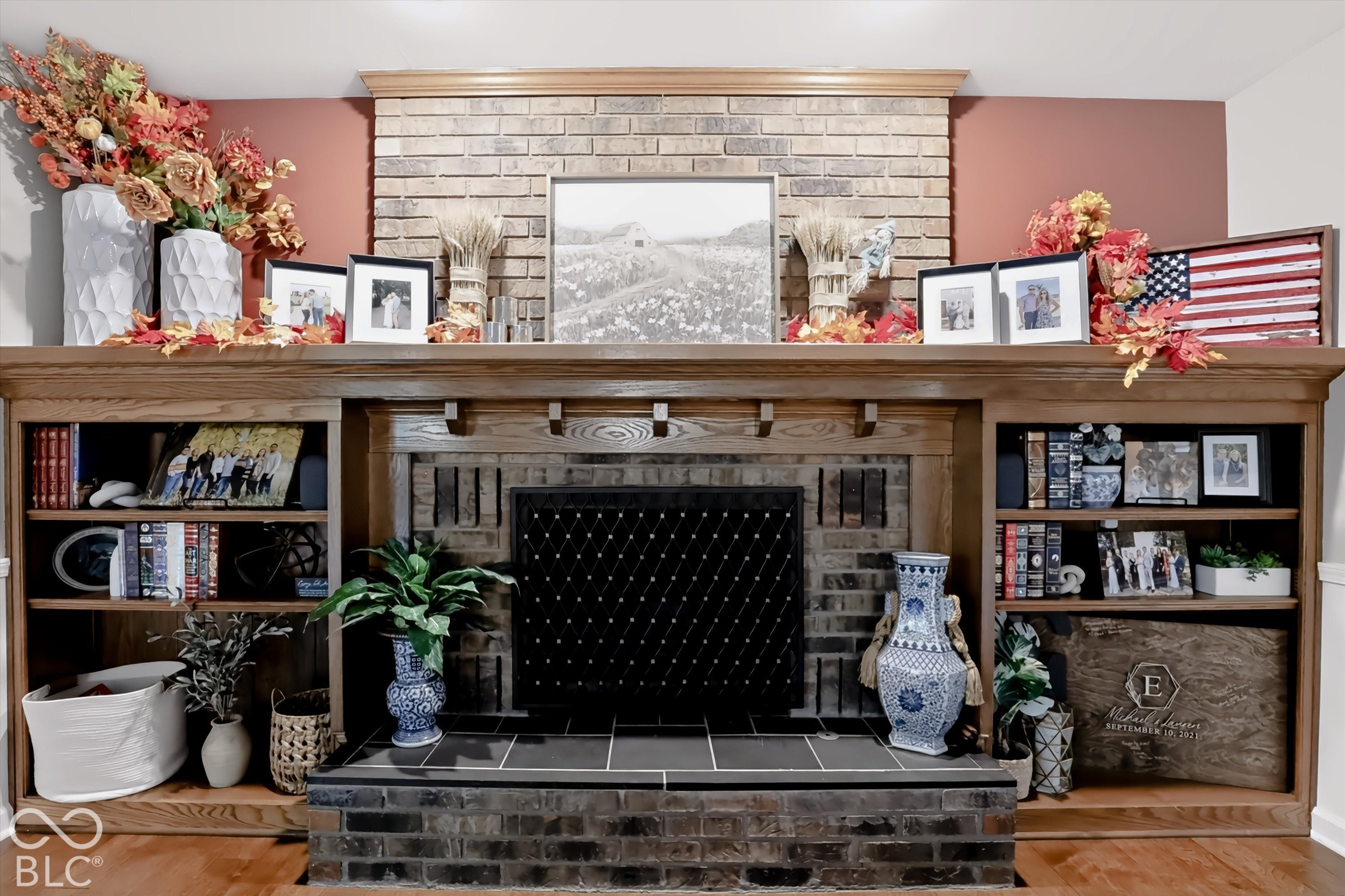 Living room fireplace with a black metal screen, gray brick surround, and decorated wooden mantel.