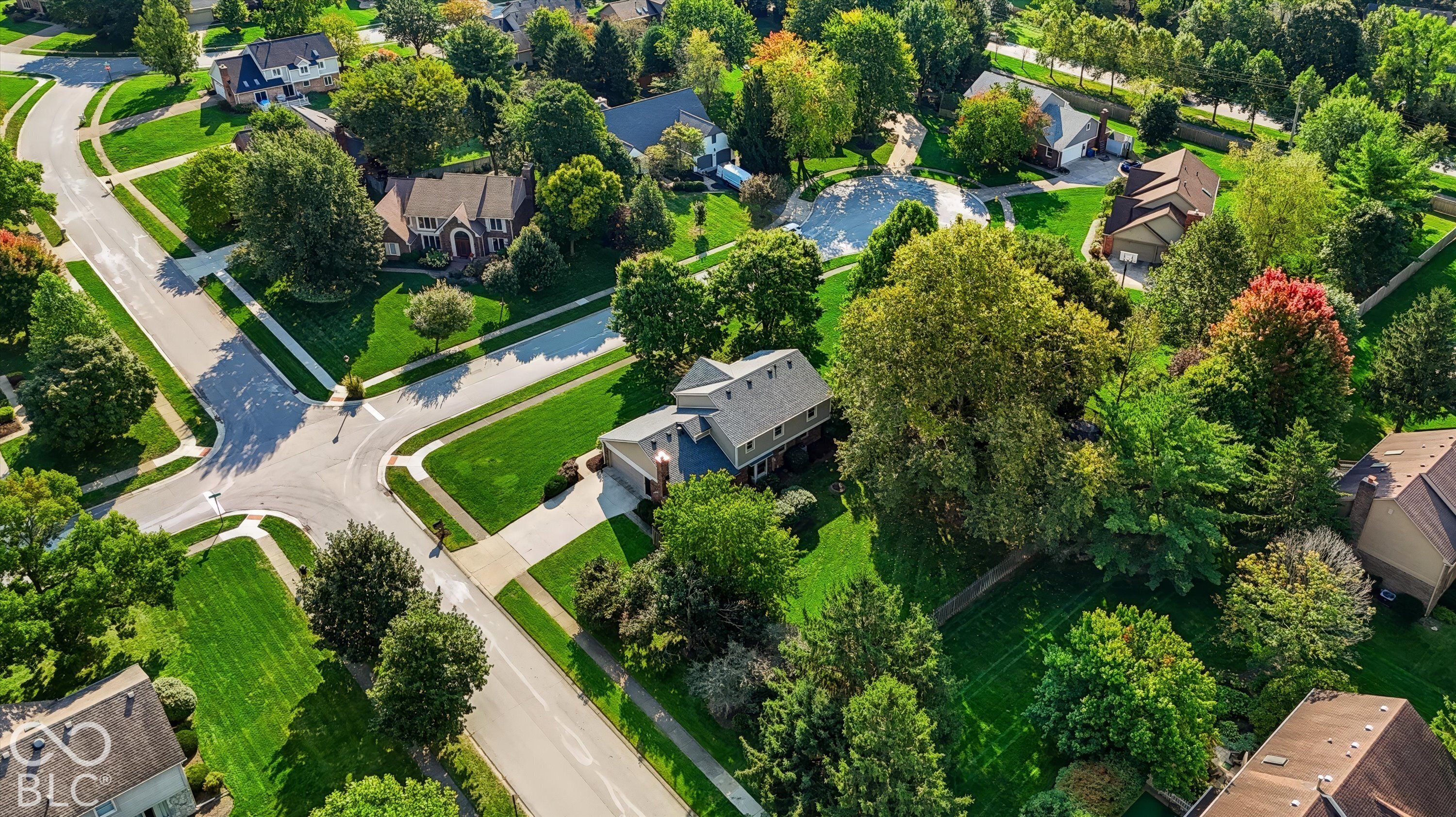 Aerial view of a home among tree-lined streets and landscaped lawns.