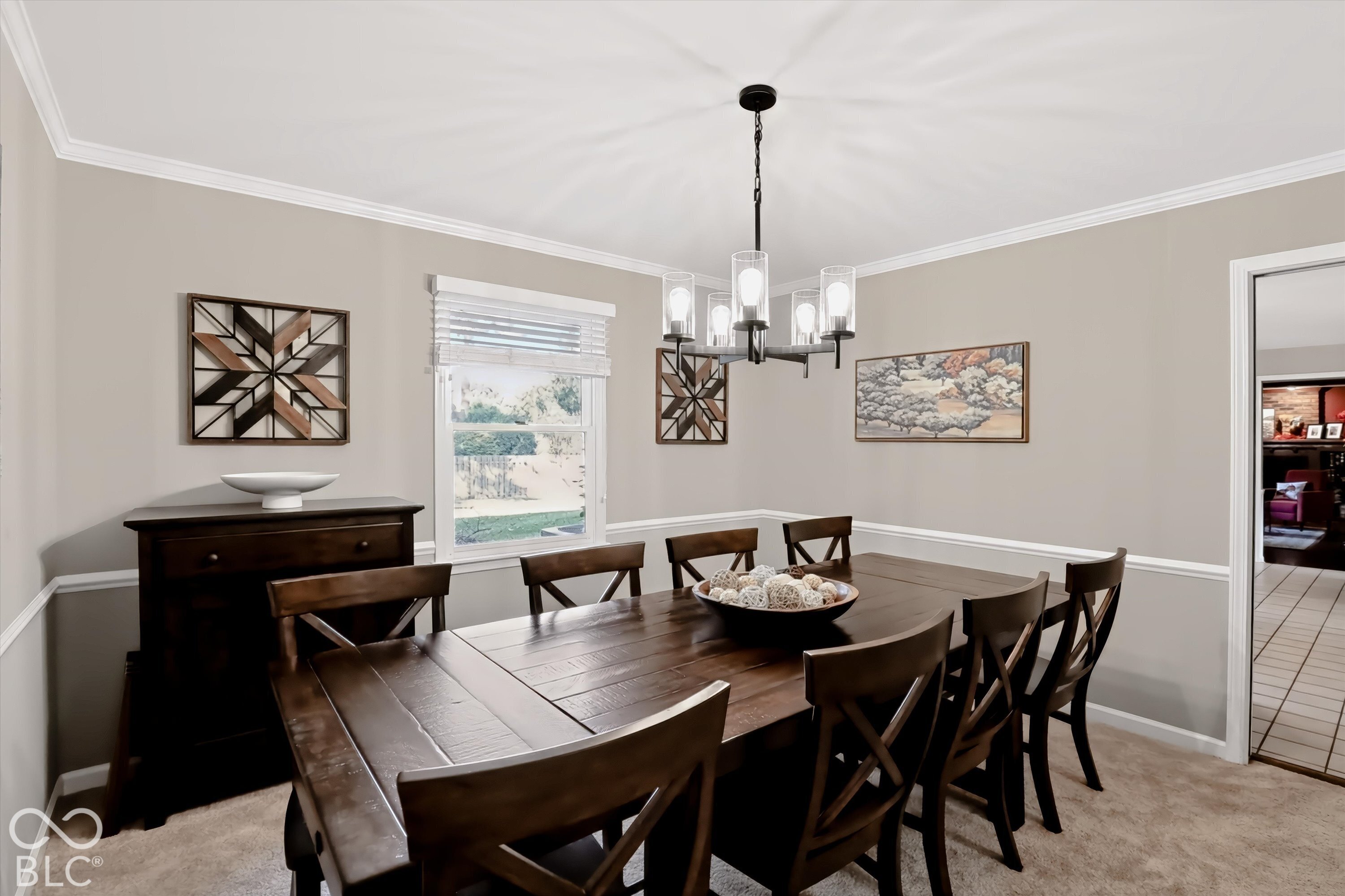 Furnished dining room with a large dark wood table, matching chairs, and a modern chandelier.