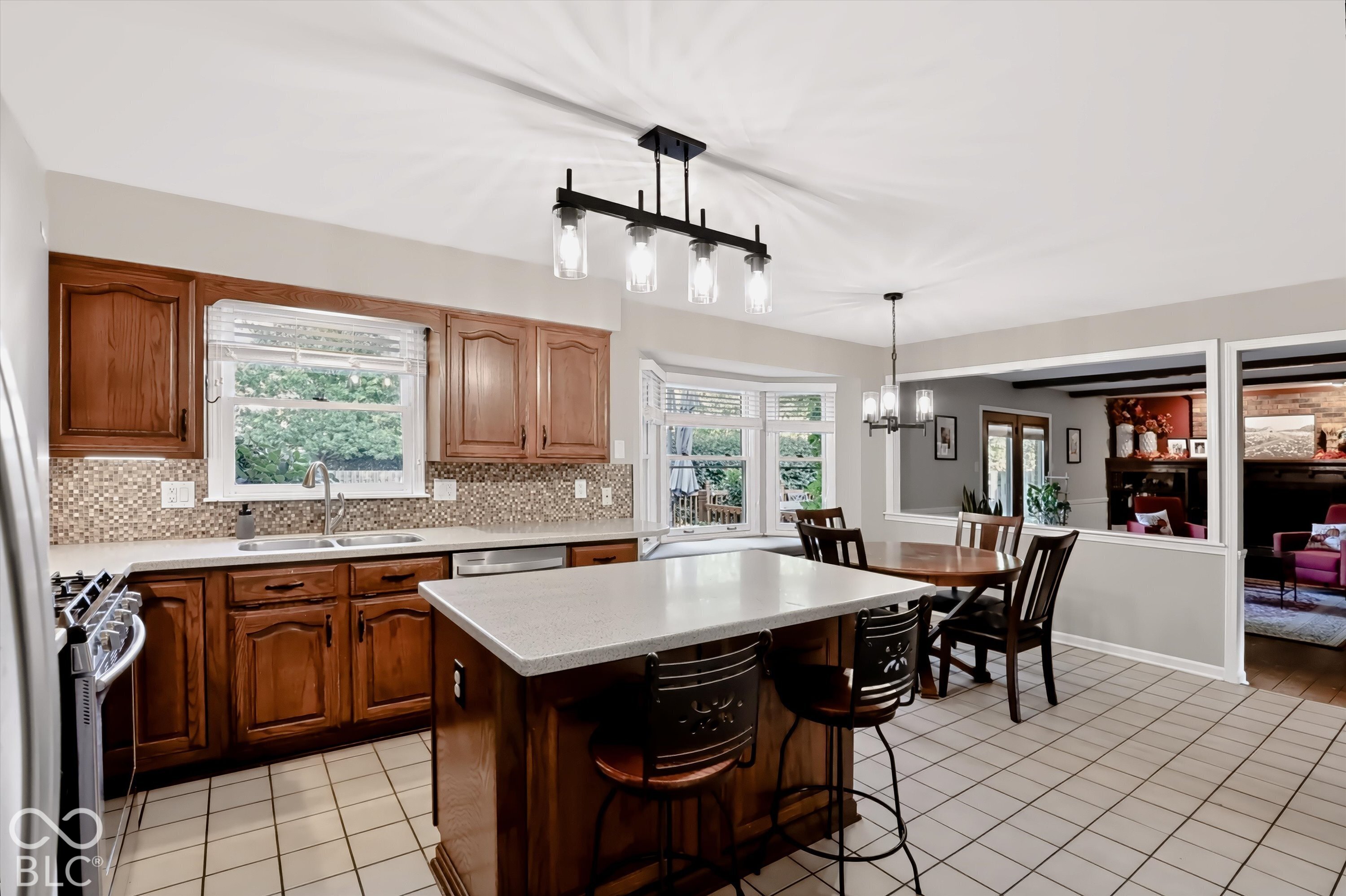 Kitchen with warm wood cabinets, mosaic backsplash, and a large island with bar stools.