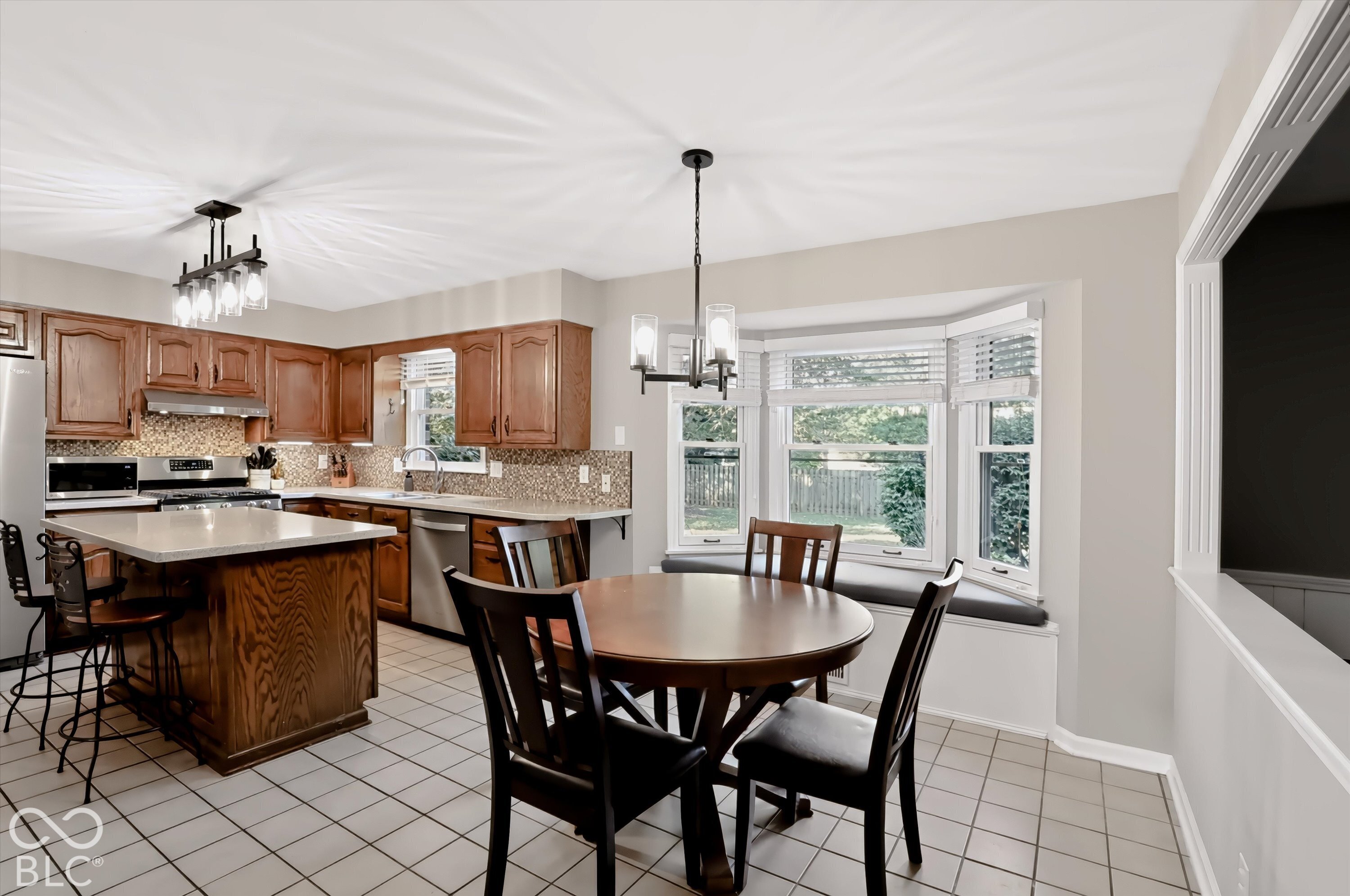 Kitchen and dining area with a wood-cabinet island, round table, and bright bay window.