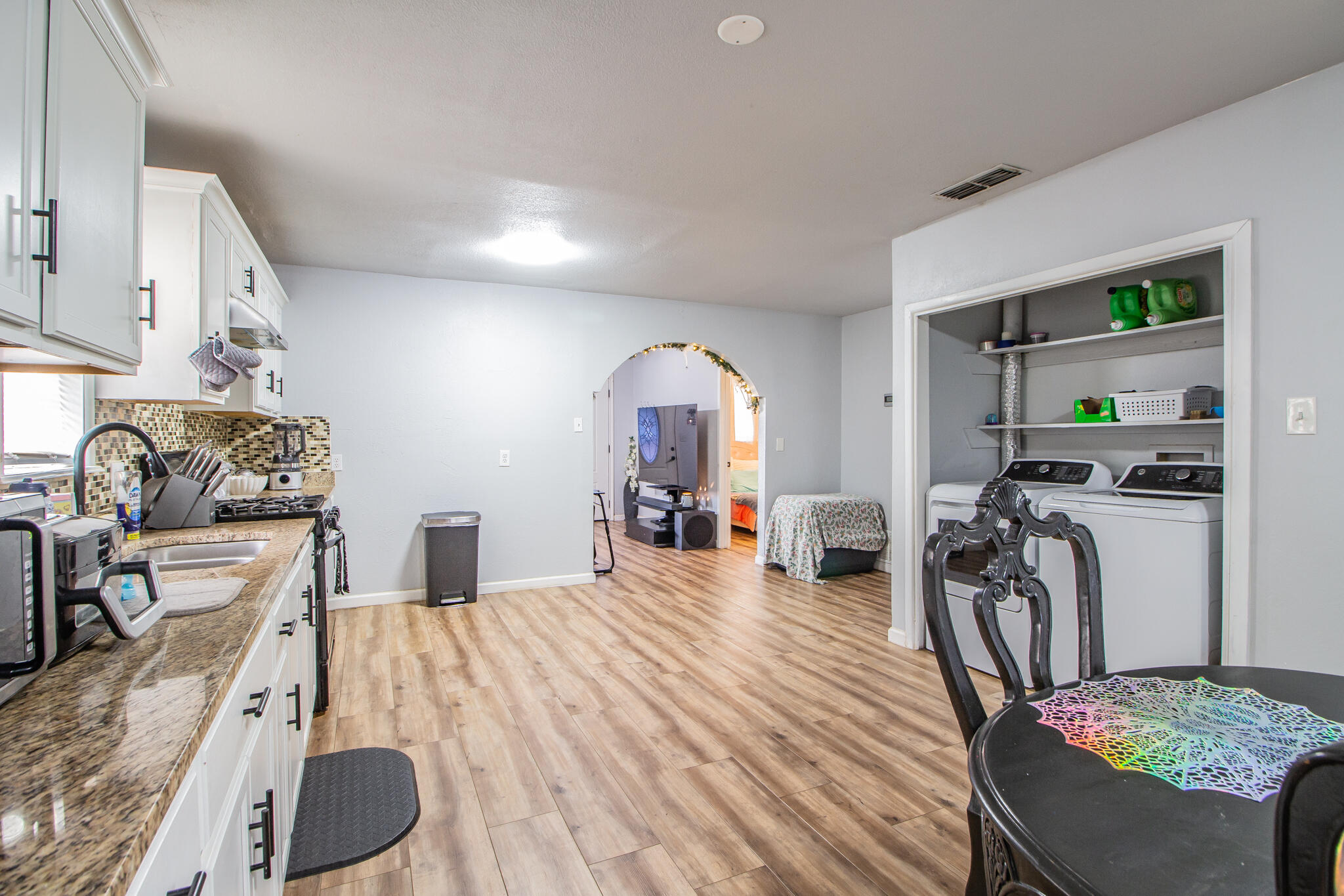 Kitchen and dining area with granite counters, wood-look flooring, and an open laundry alcove.