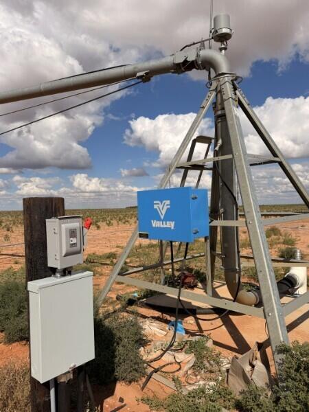 Metal agricultural equipment with a blue Valley control box in a dry field.