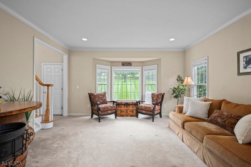 Living room with a tan sofa, patterned armchairs, and a bay window overlooking a green lawn.