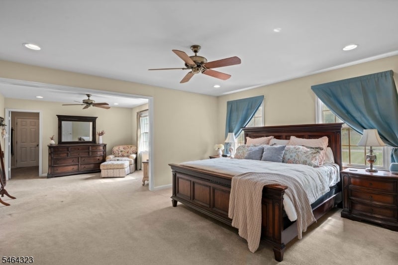 Primary bedroom with a dark wood bed, blue curtains, and an adjoining sitting area.