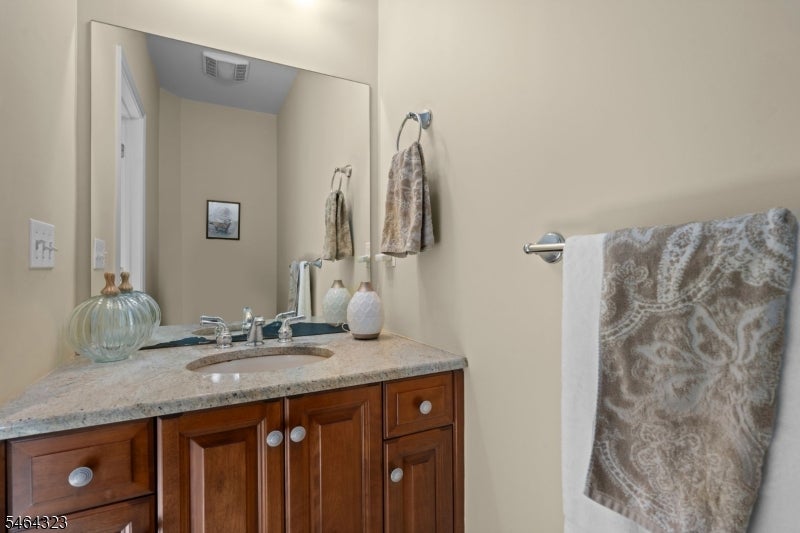 Bathroom vanity with a stone countertop, dark wood cabinets, and patterned towels.