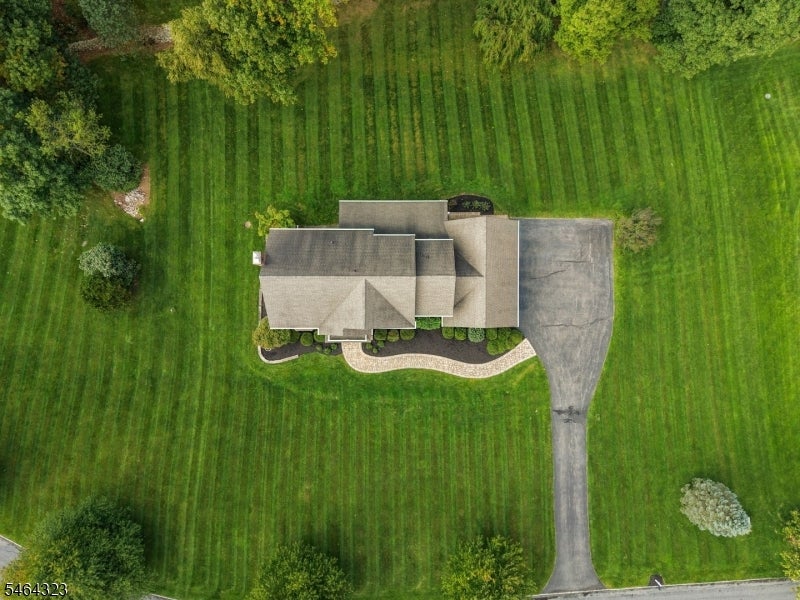 Aerial view of a home on a striped lawn, with a curved walkway and long driveway.