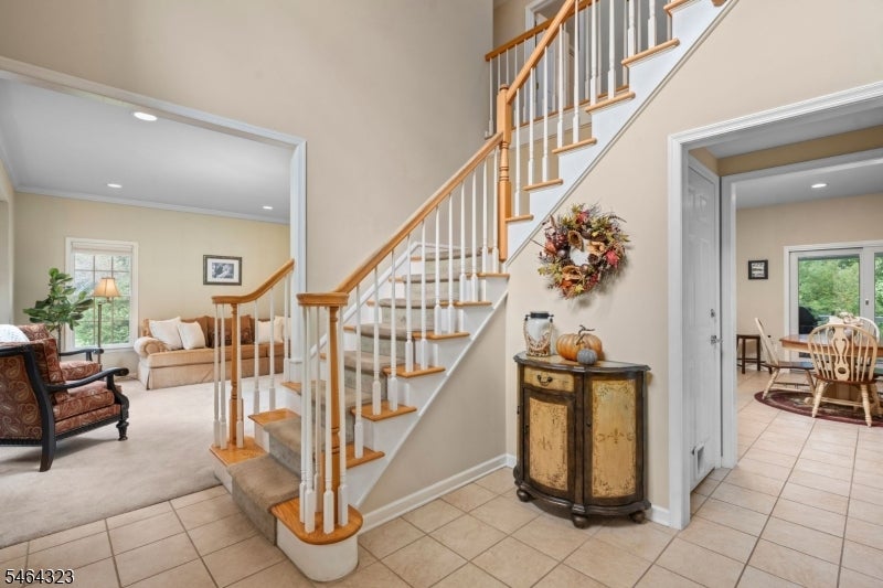 Entry foyer with a sweeping wood-and-white staircase, tiled floor, and adjoining living and dining rooms.