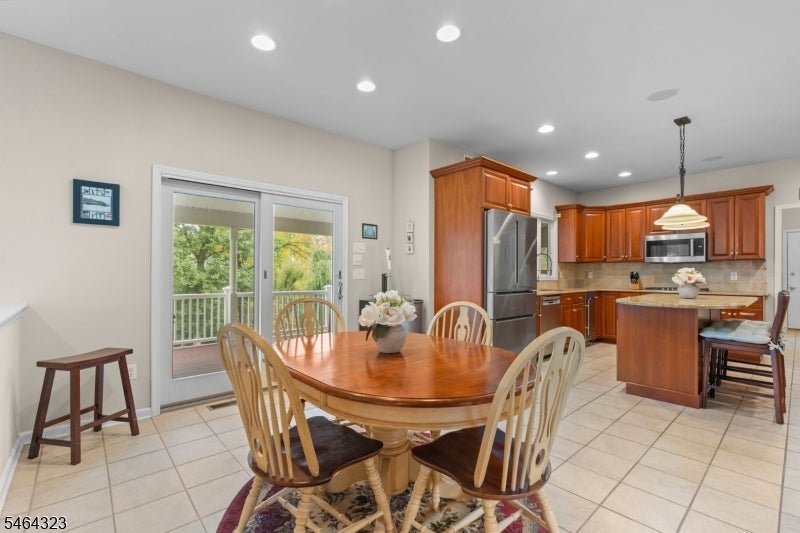 Open kitchen and dining area with reddish wood cabinets, a round table, and sliding doors to a deck.