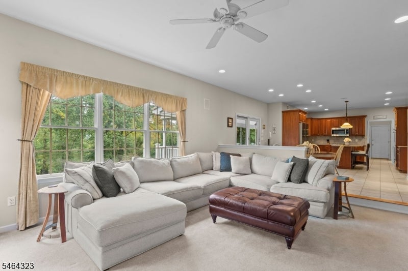 Furnished living room with a large sectional, leather ottoman, and open kitchen.