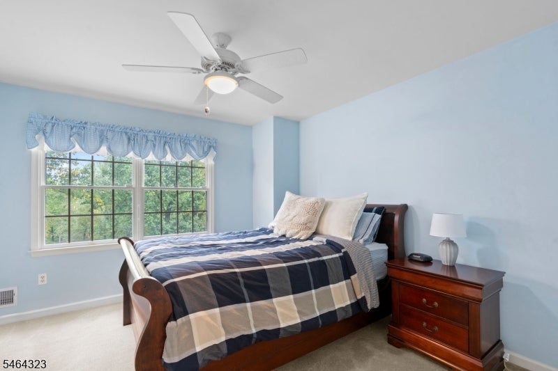 Bedroom with blue walls, plaid bedding, two windows, and dark wood furniture.