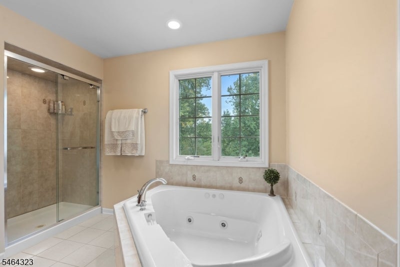 Bathroom with a jetted soaking tub beneath a window and a glass-enclosed shower.