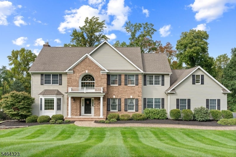 Two-story home with a brick center facade, light siding, and a broad striped lawn.