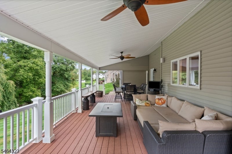 Covered deck with wicker sectional seating, dining set, and views of trees and neighboring homes.