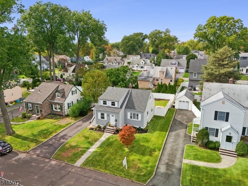 Aerial view of a gray-sided house on a landscaped corner lot in a tree-lined neighborhood.