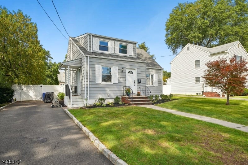Gray two-story house with a front dormer, white trim, driveway, and lawn.