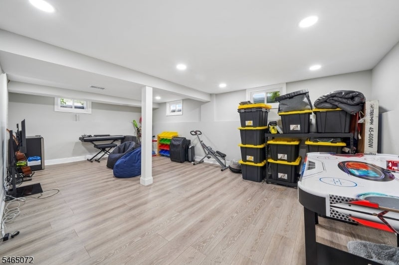 Finished basement recreation room with exercise equipment, stacked storage bins, and an air hockey table.
