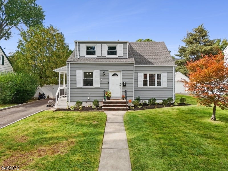 Gray-sided home with a dormer, front lawn, and walkway to the entrance.