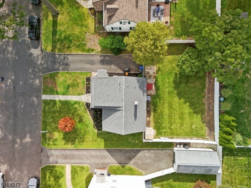 Aerial view of a home with a broad lawn, driveway, and neighboring houses.