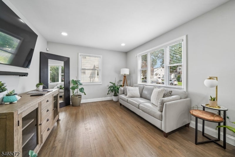 Living room with a white sofa, wide windows, wood floors, and a rustic media console.