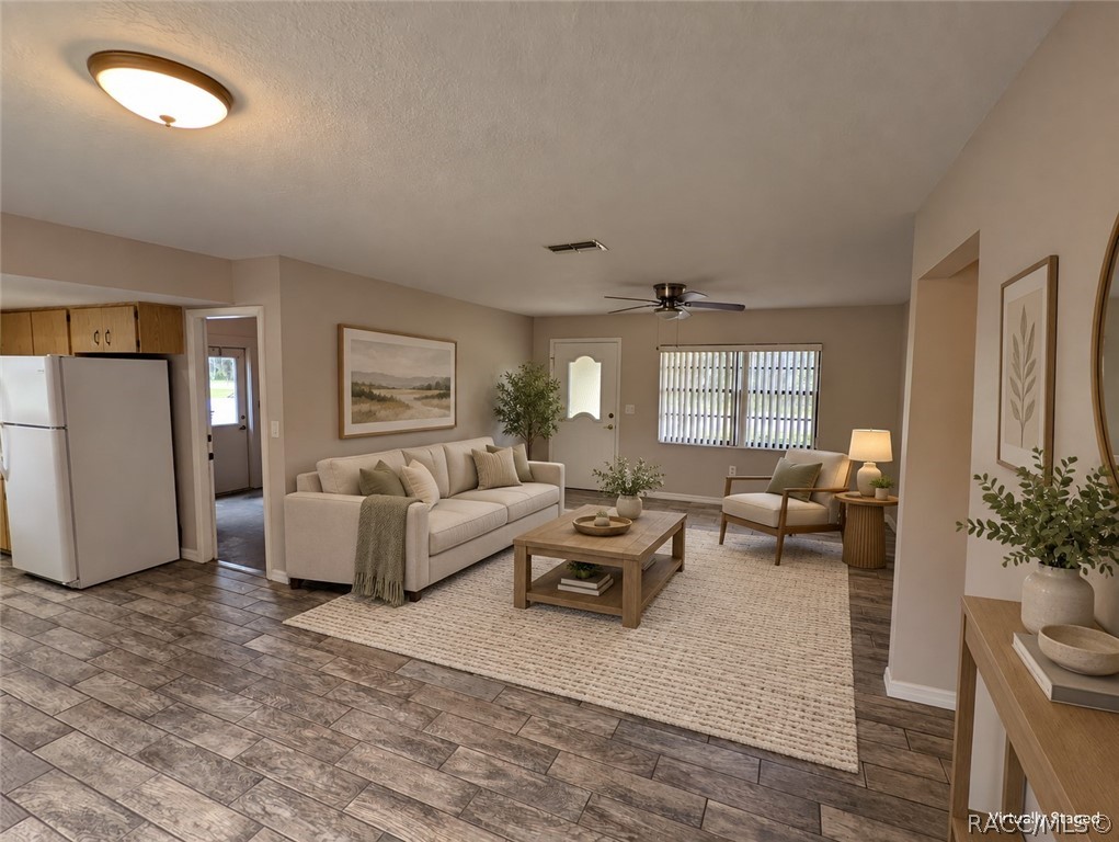 Virtually staged living room with a cream sofa, wood coffee table, and window with vertical blinds.