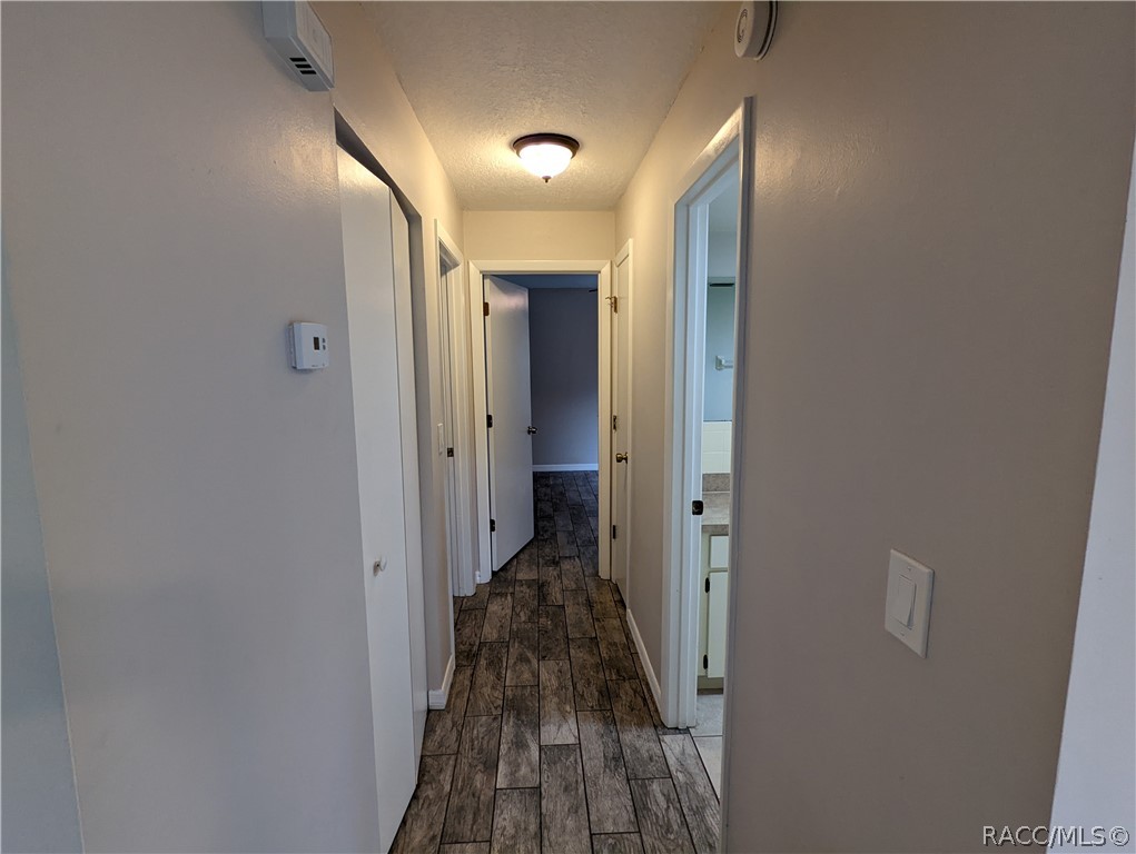 Hallway with dark wood-look tile flooring and several open doorways.