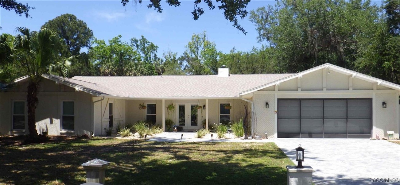Single-story home with a covered entry, attached two-car garage, and mature trees.