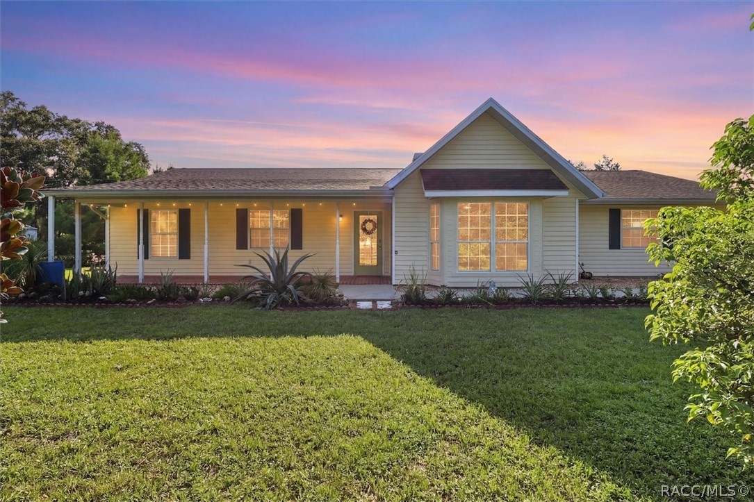 Single-story home with a covered porch and front gable, warmly lit beneath a pink sunset sky.