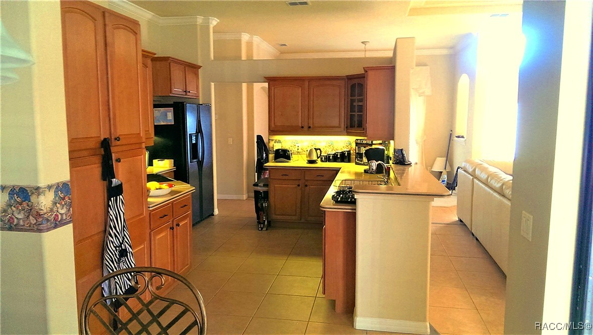 Kitchen with warm wood cabinets, a tiled floor, and a long peninsula with a cooktop.