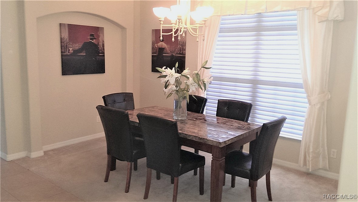 Dining room with a stone-top table, six dark chairs, and a chandelier.