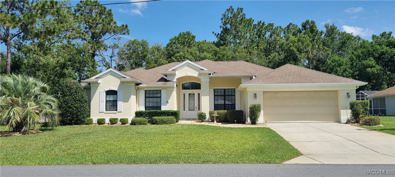 Pale yellow single-story home with an arched entry, two-car garage, and broad front lawn.