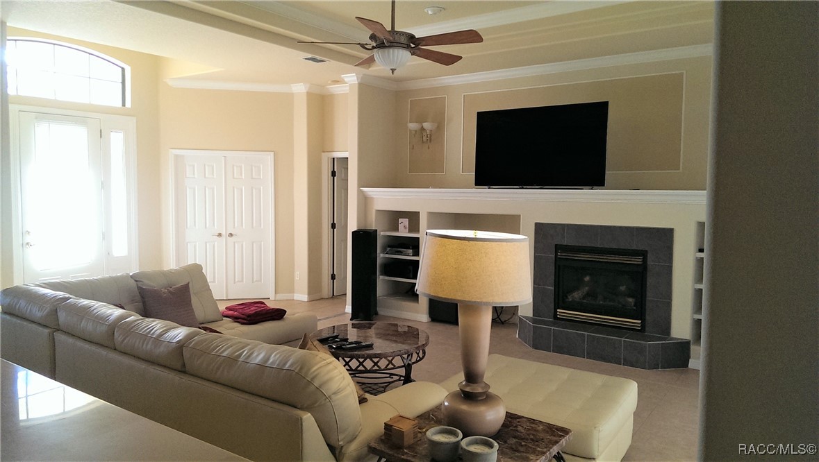 Furnished living room with a leather sectional and tiled fireplace beneath a wall-mounted television.