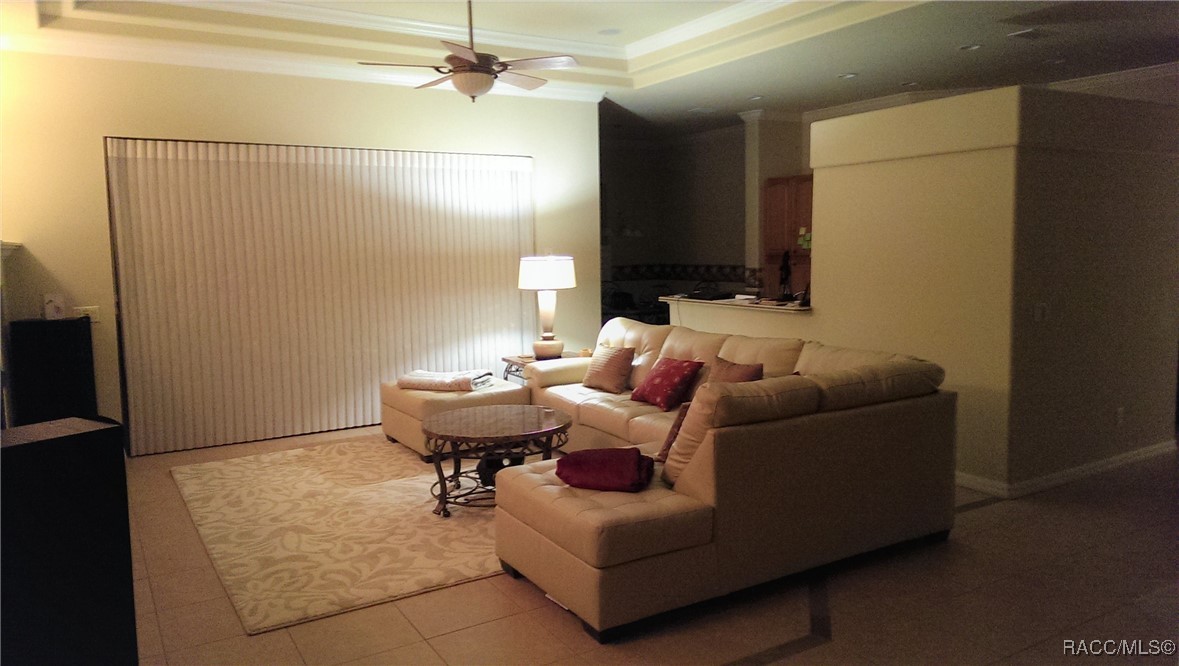 Furnished living room with a beige sectional, patterned rug, and vertical blinds.