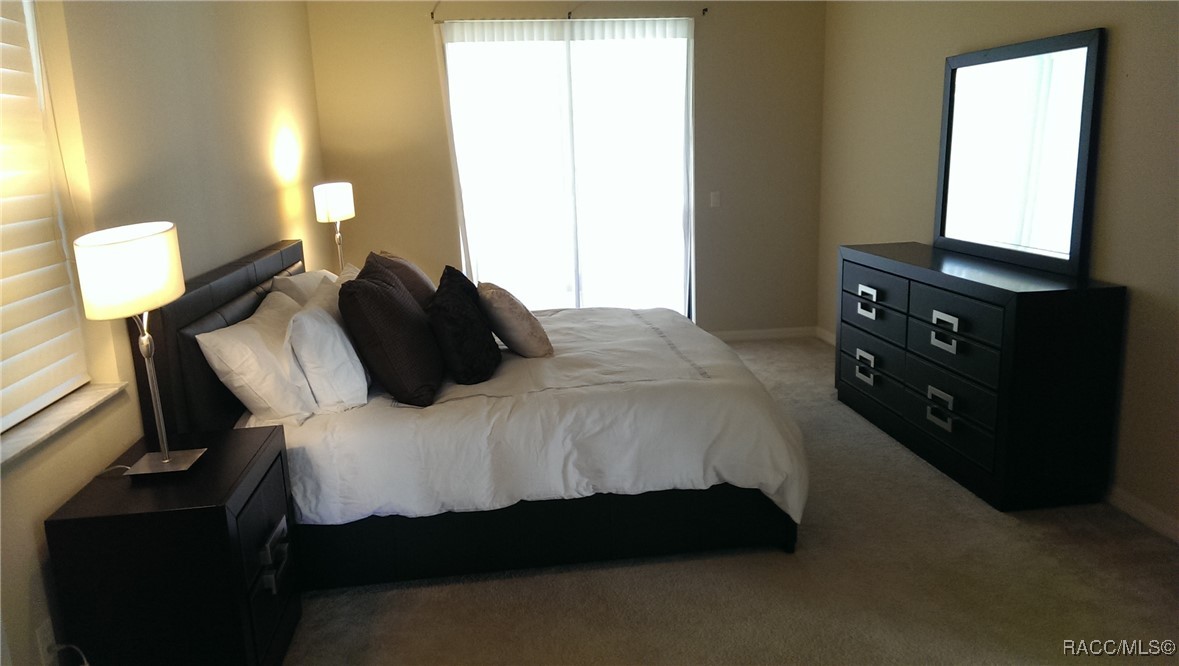 Bedroom with a white-bedded king-size bed, dark furniture, and bright windows.