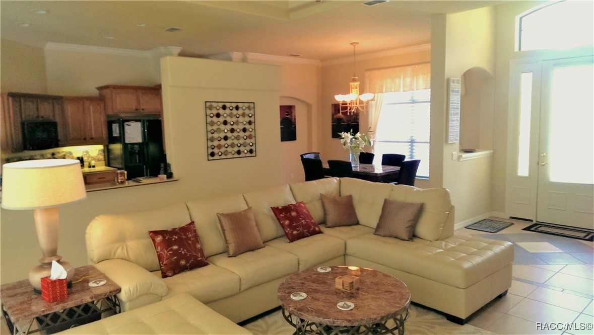 Furnished living room with a cream sectional, open kitchen pass-through, and dining area.