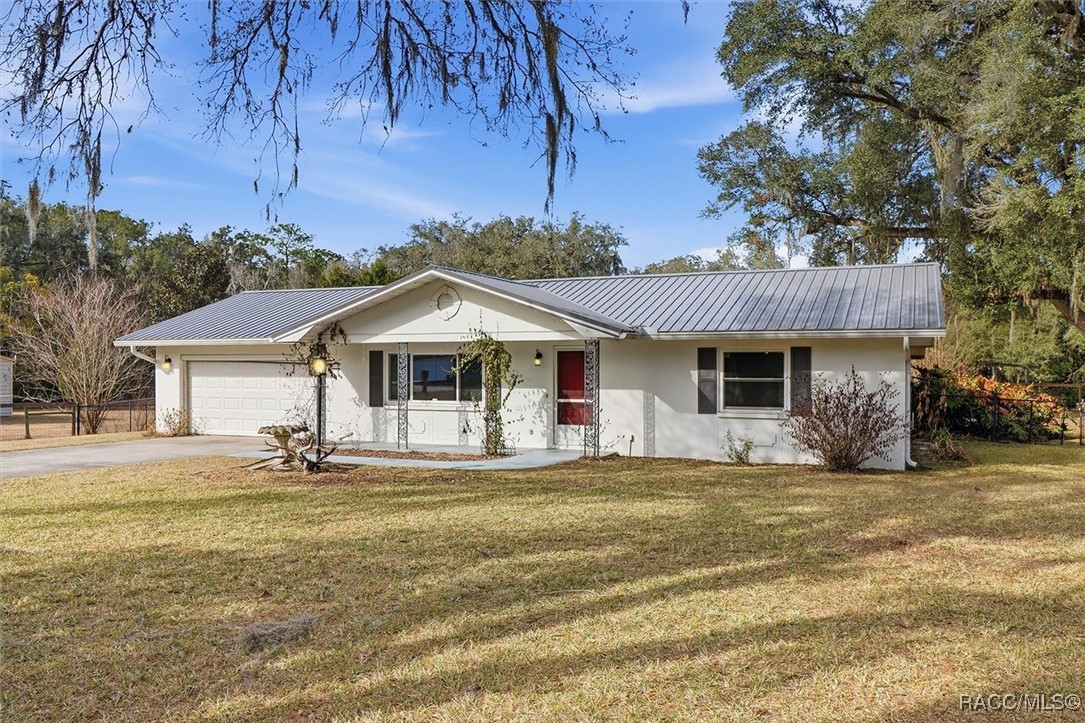 Single-story white home with a gray metal roof, attached garage, and red front door.