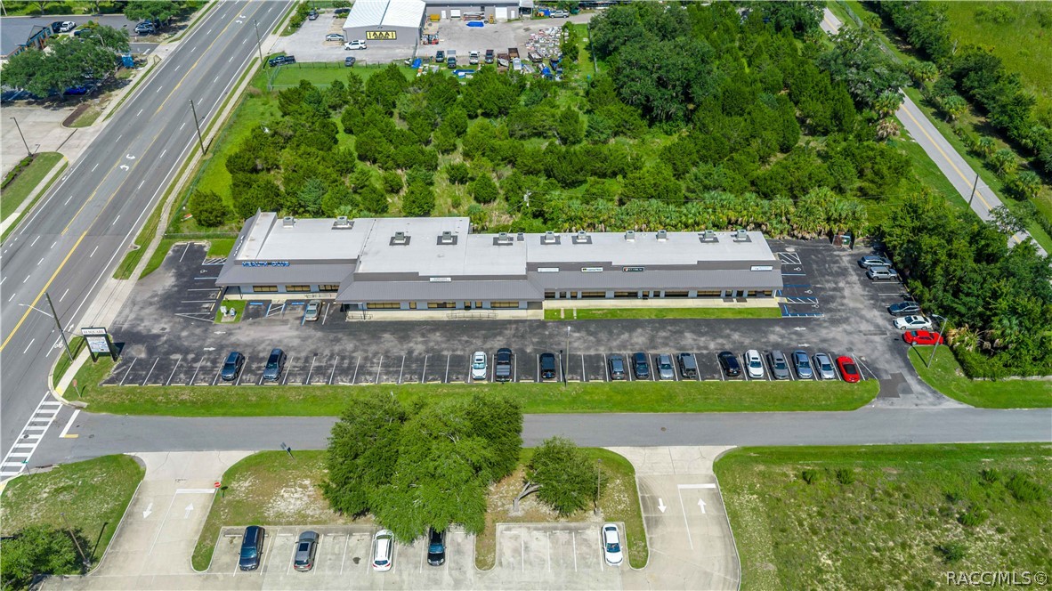 Aerial view of a single-story commercial building and parking lot beside a multi-lane road.