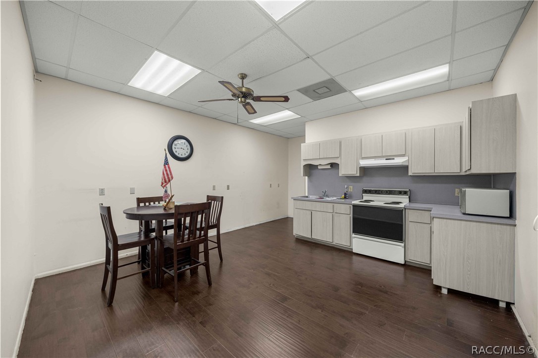 Kitchenette with light wood cabinets and stove beside a dining table with chairs.