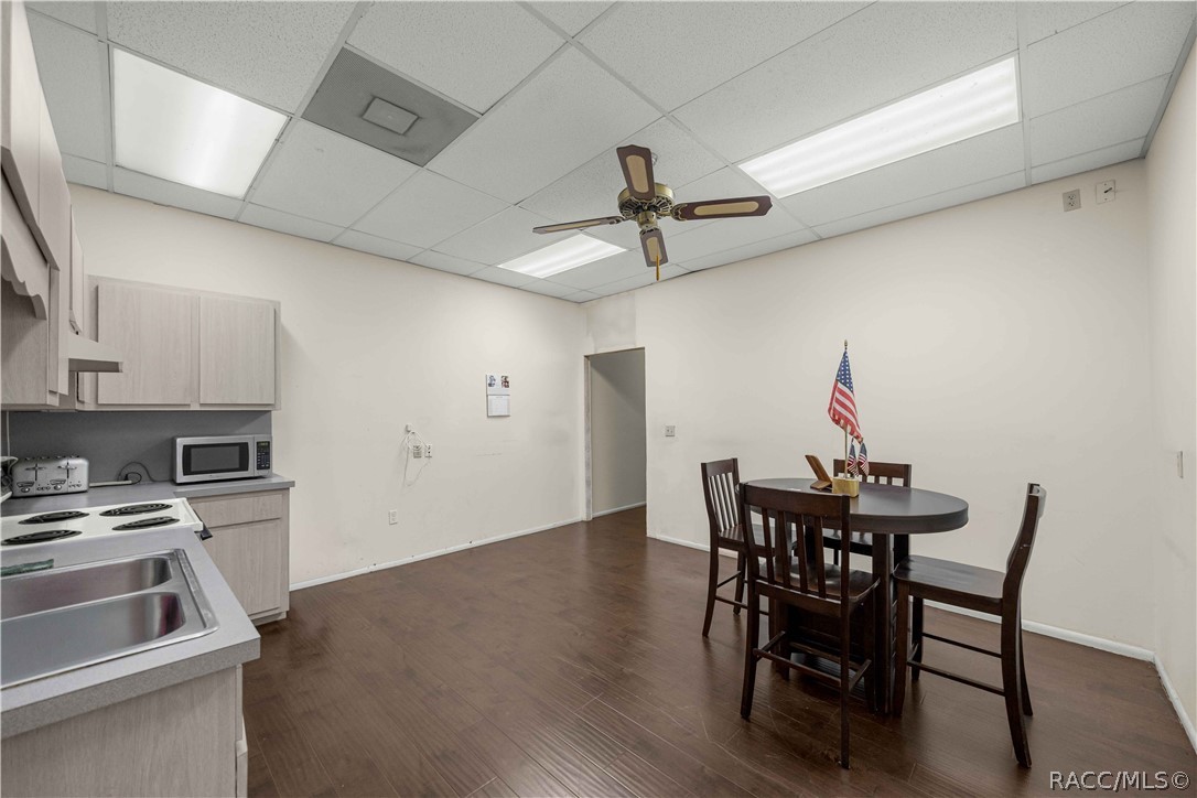 Kitchenette and dining area with light wood cabinets and a dark round table with chairs.
