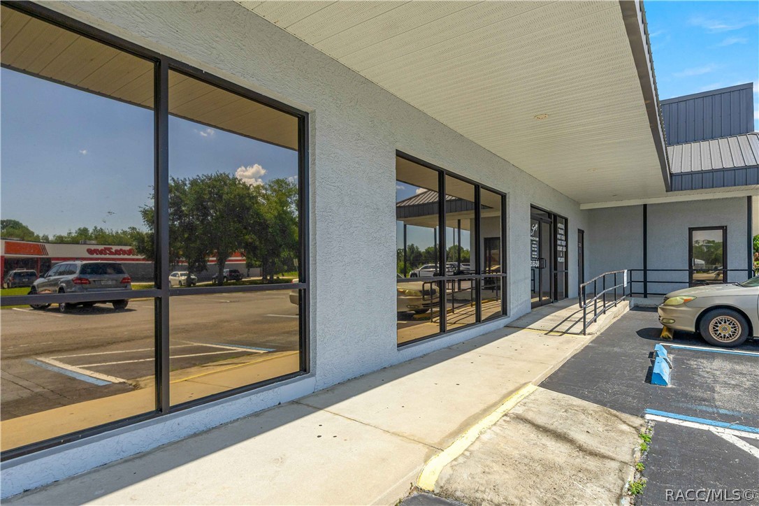 Commercial storefront with reflective windows, a covered walkway, and an accessibility ramp.
