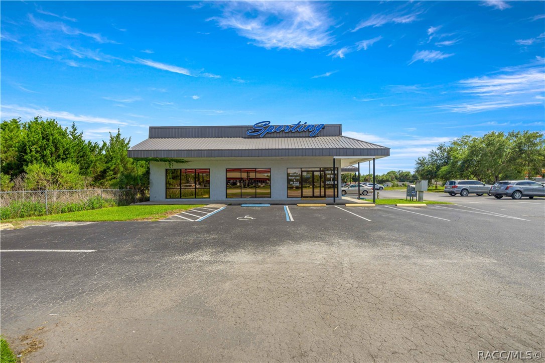 Single-story Sporting storefront with a wide metal roof, large windows, and a paved parking lot.