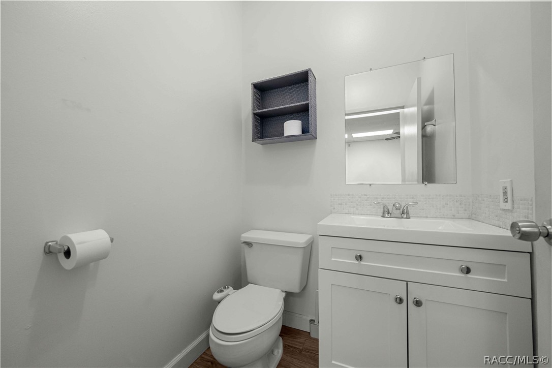 Bathroom with a white vanity, toilet, rectangular mirror, and mosaic tile backsplash.