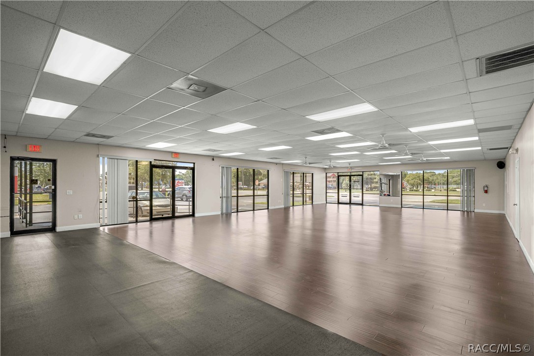 Vacant commercial interior with broad open flooring and street-facing glass doors and windows.