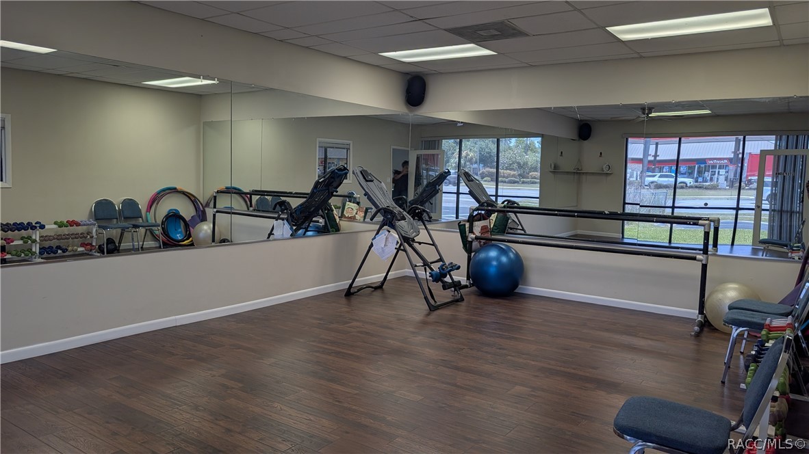 Fitness room with exercise equipment, mirrored walls, and large street-facing windows.