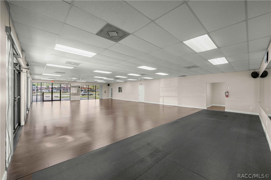 Vacant commercial interior with open flooring, glass storefront, and suspended ceiling.