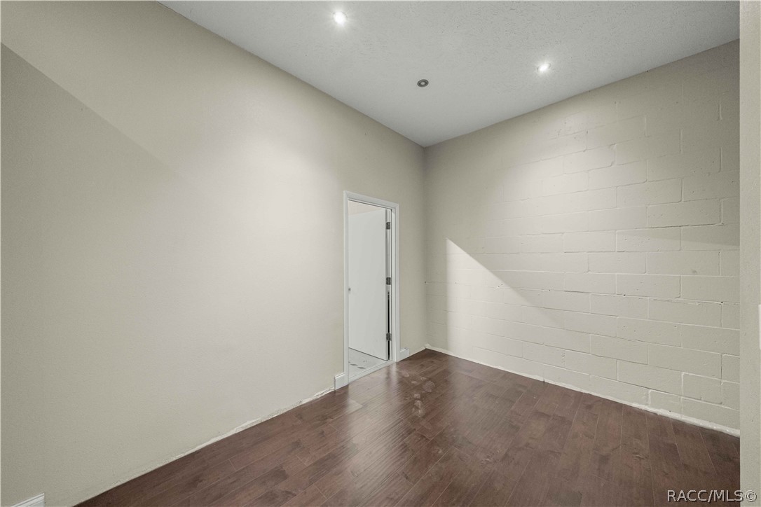 Empty room with wood-look flooring and a painted block wall.
