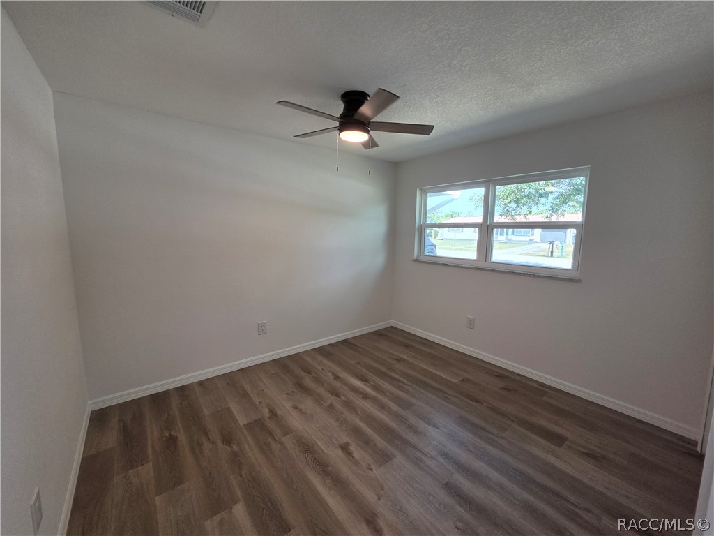 Vacant room with wood-look flooring, a ceiling fan, and a double window.
