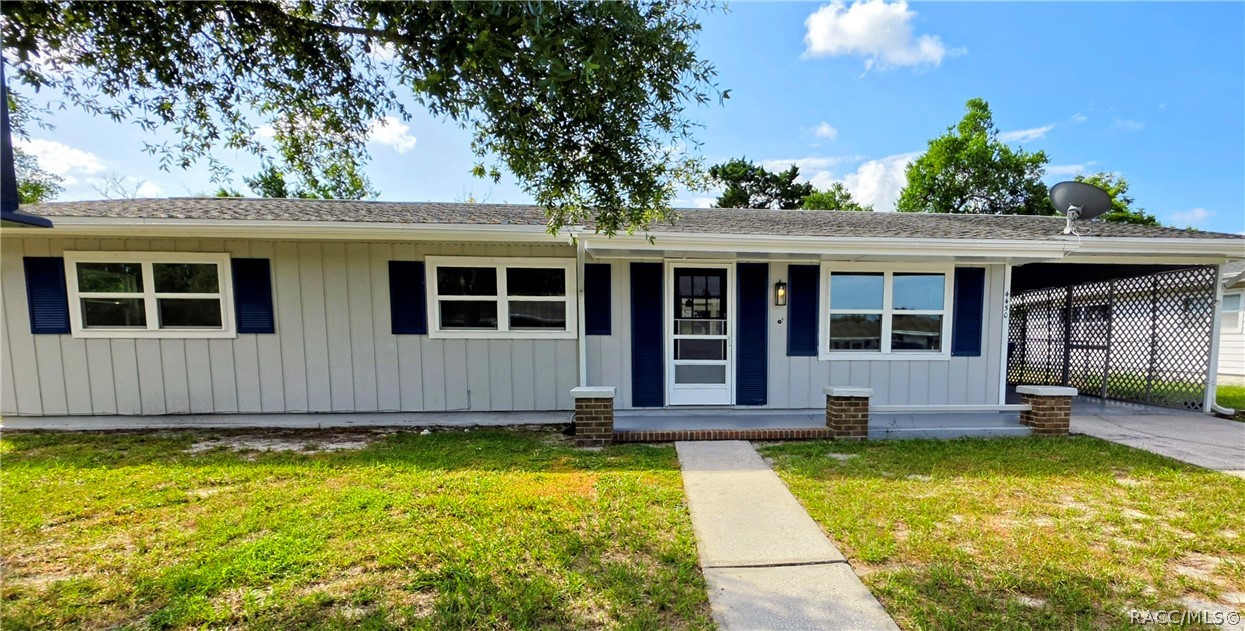Single-story gray home with navy shutters, a central entry, and a lattice-covered carport.