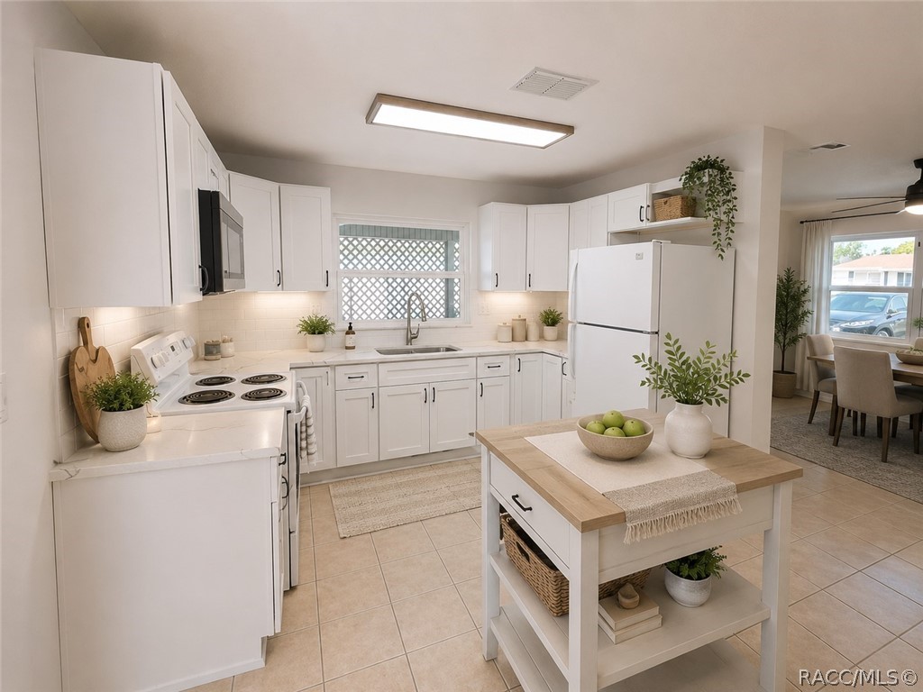 Bright white kitchen with a wood-topped island and a dining area visible beyond.