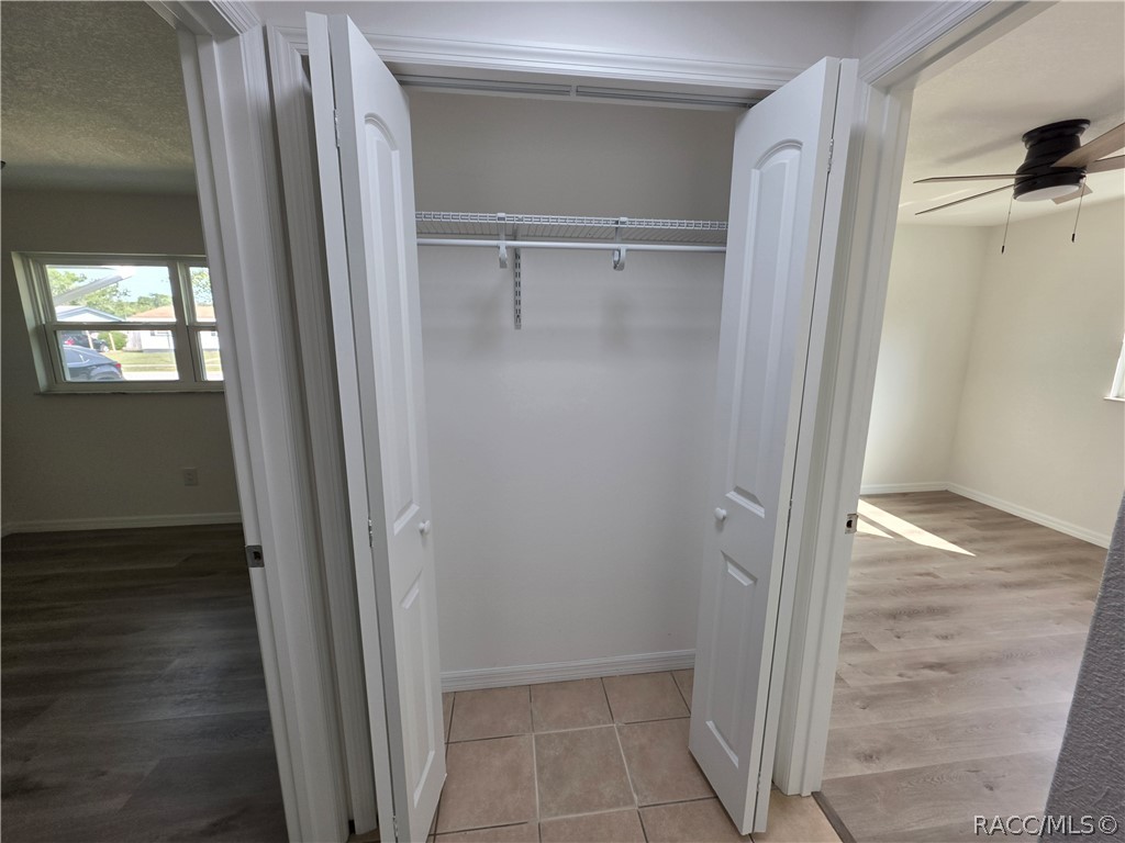 Open empty closet with wire shelving and tiled floor, between two rooms.